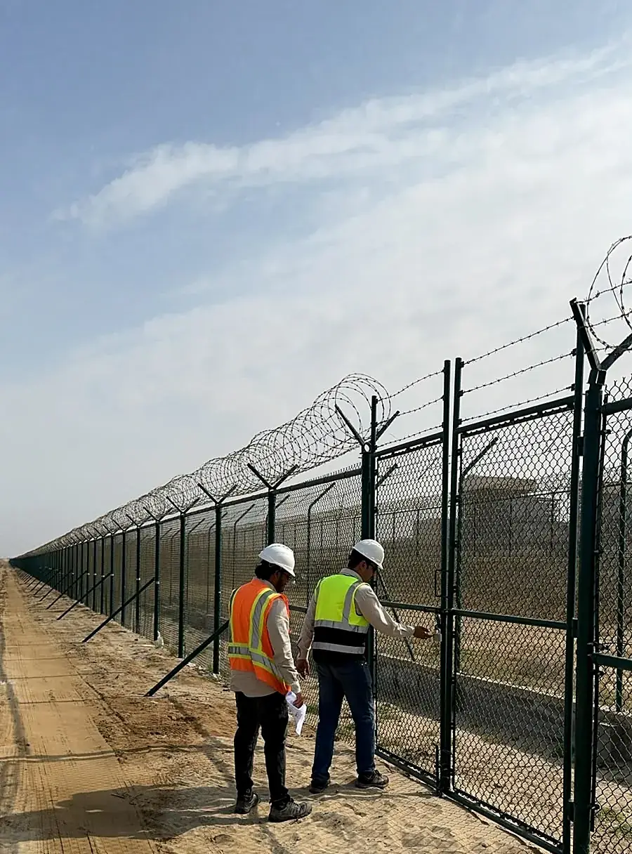 Site team checking a fence gate and barbed wire